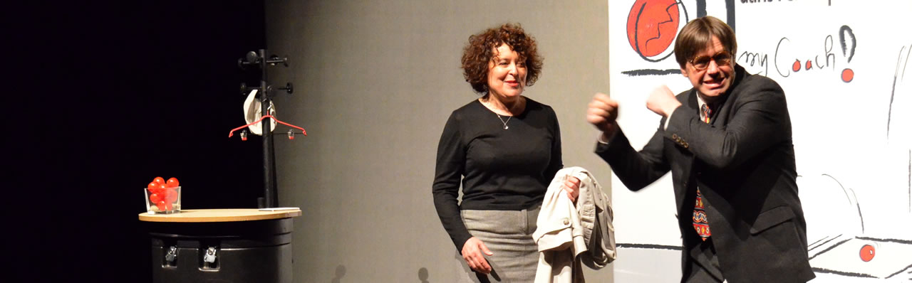 Extrait du spectacle : l'homme gesticule devant la femme amusée.