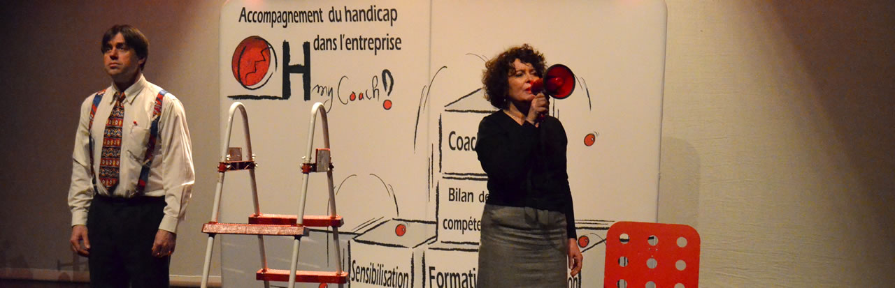 Extrait du spectacle : la femme parle dans un porte-voix rouge, l'homme est immobile à côté d'un escabeau.