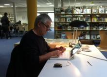 Jacques Jouet écrit un livre dans les locaux de la bibliothèque universitaire de Metz.