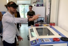 Utilisateur avec un casque de réalité augmentée Hololens 2 devant les yeux qui pointe du doigt un objet virtuel 