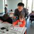 Des enfants pratiquent la caligraphie chinoise sous l'oeil d'un animateur.